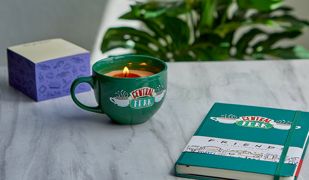 Friends Central Perk coffee cup candle from Insight Editions, featuring a ceramic mug with Central Perk logo and cozy design.