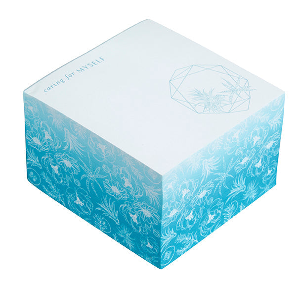 Insight Editions Self-Care Memo Cube on a desk, featuring motivational quotes and a sleek home goods design.