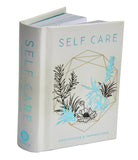 Insight Editions Self-Care Gift Set kit with skincare products and relaxation items arranged in a decorative box.