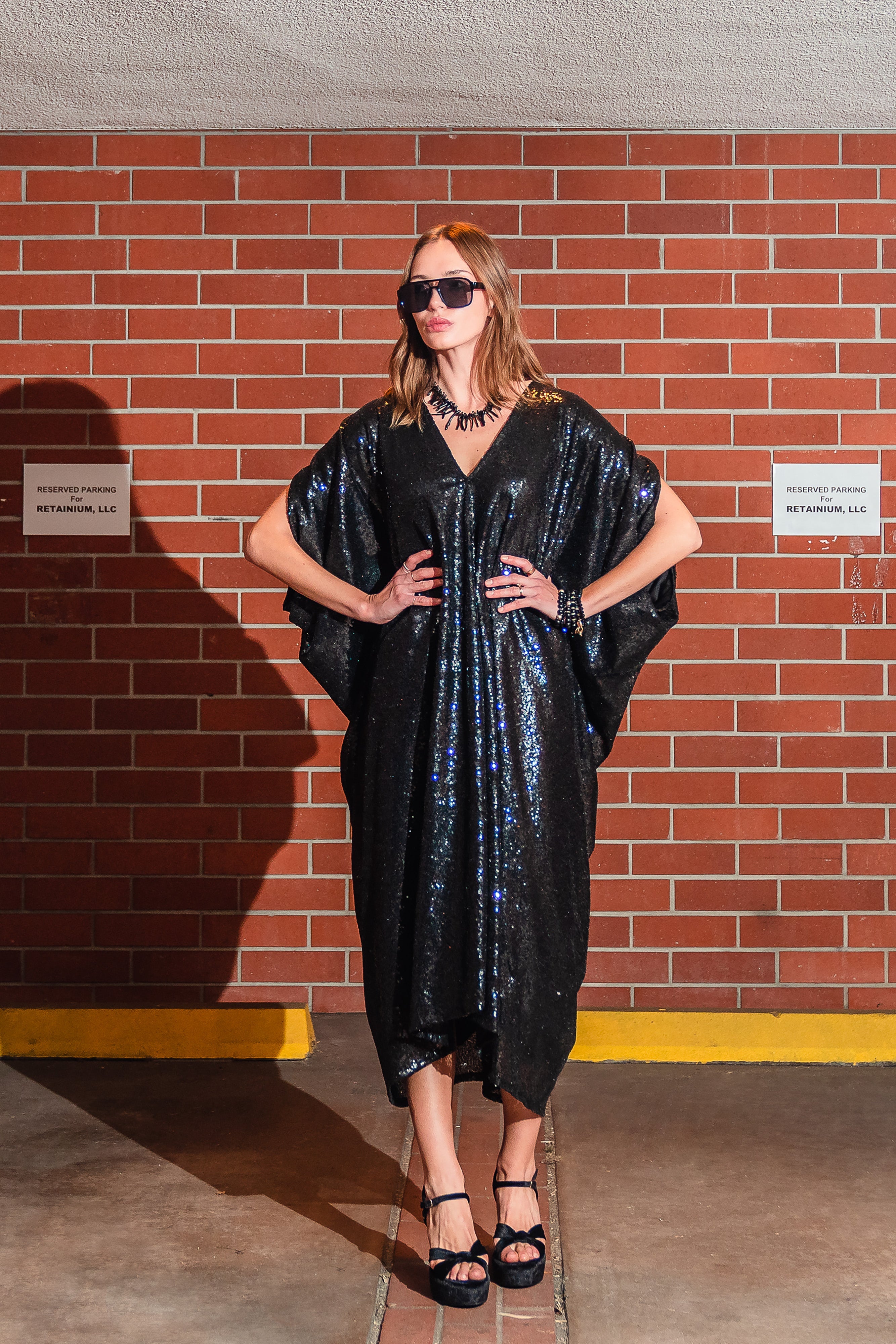 Black sequin caftan dress by Jennafer Grace featuring shimmering sequins and flowing fabric, displayed on a mannequin.