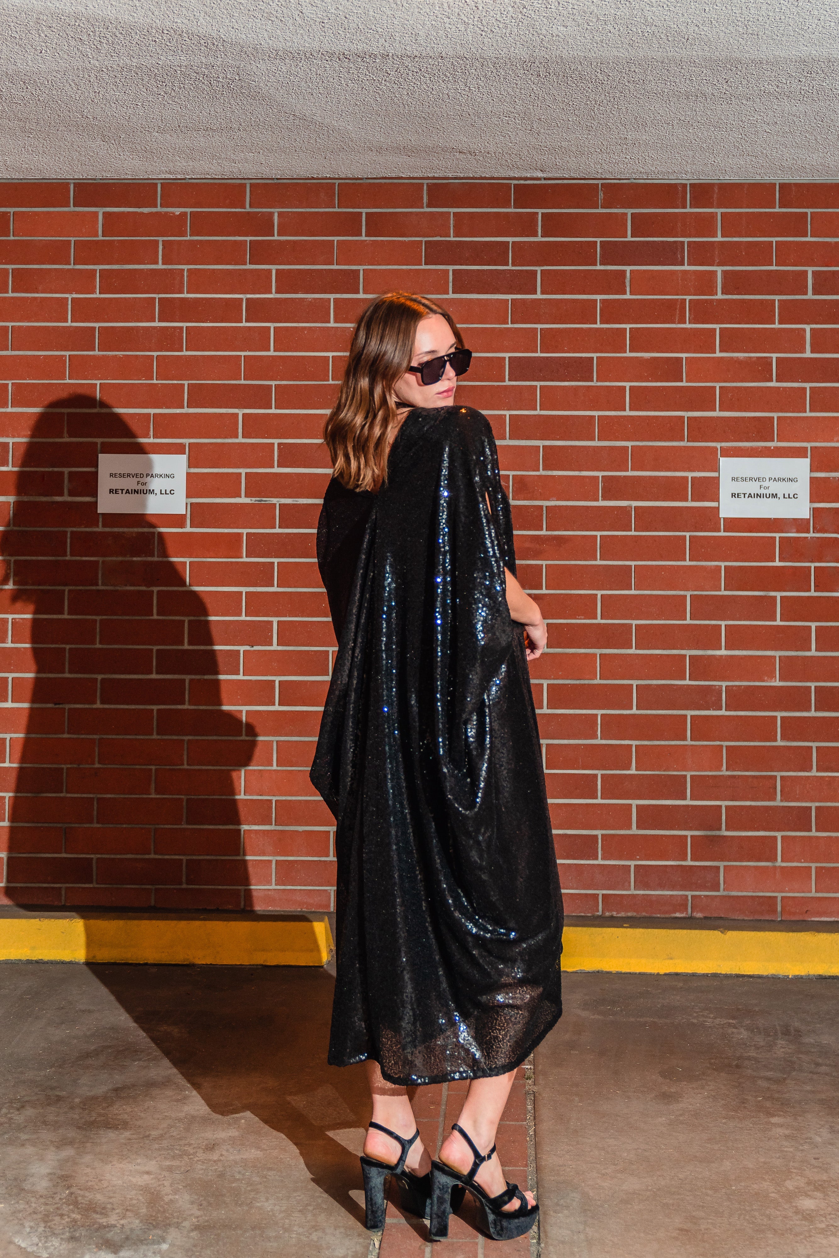 Black sequin caftan dress by Jennafer Grace featuring hand-stitched embellishments and flowing fabric for elegant style.