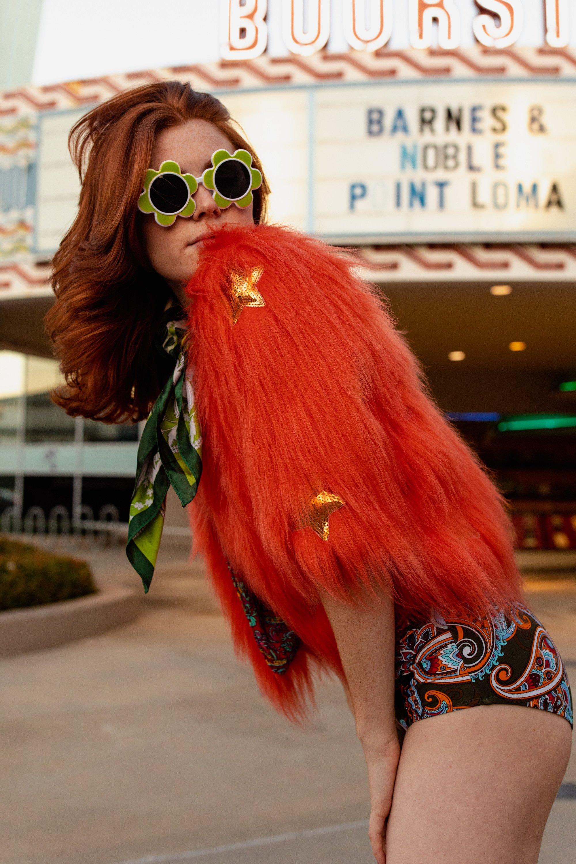 Girl wearing Jennafer Grace Planet Queen orange faux fur jacket, stylish and cozy outerwear with vibrant orange plush fur.