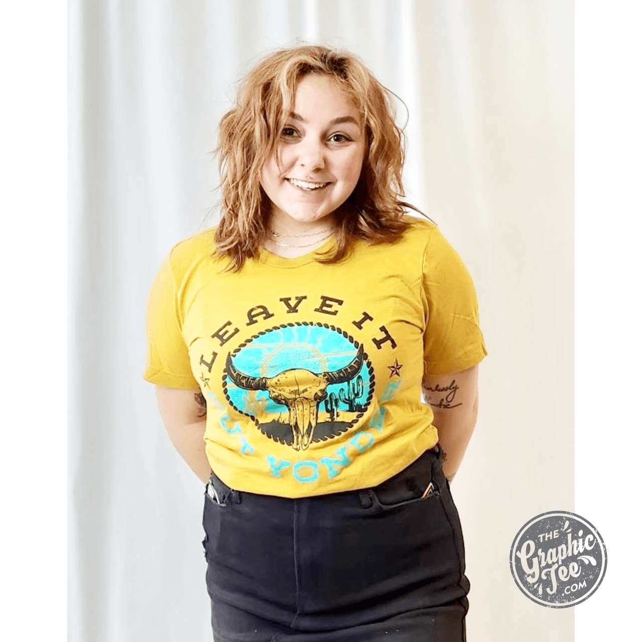 The Graphic Tee Leave It Out Yonder Mustard short sleeve graphic t-shirt with outdoor design on beige fabric.