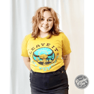 The Graphic Tee Leave It Out Yonder Mustard short sleeve graphic t-shirt with outdoor design on beige fabric.