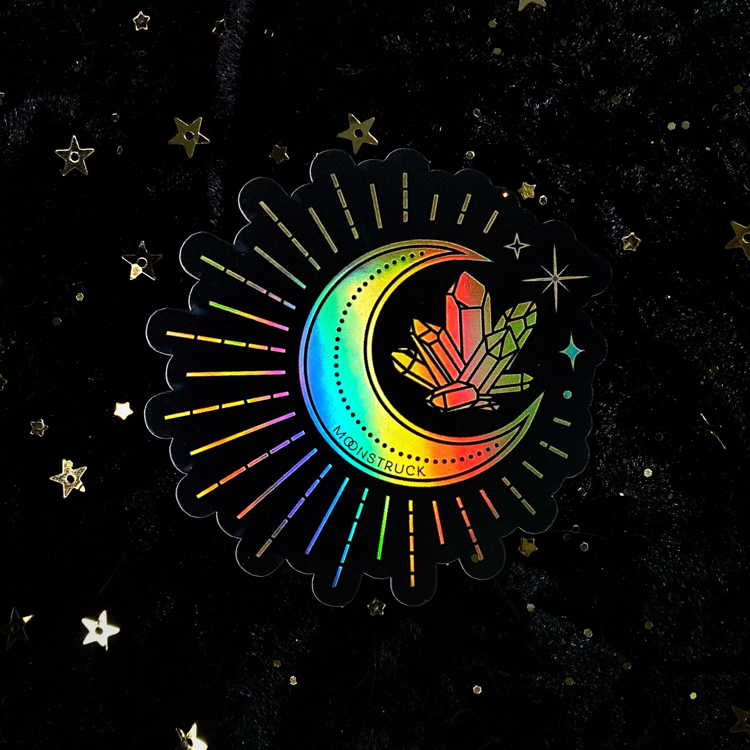 Holographic gold moon crystal sticker from Moonstruck Crystals, featuring a shimmering iridescent moon design on a clear background.