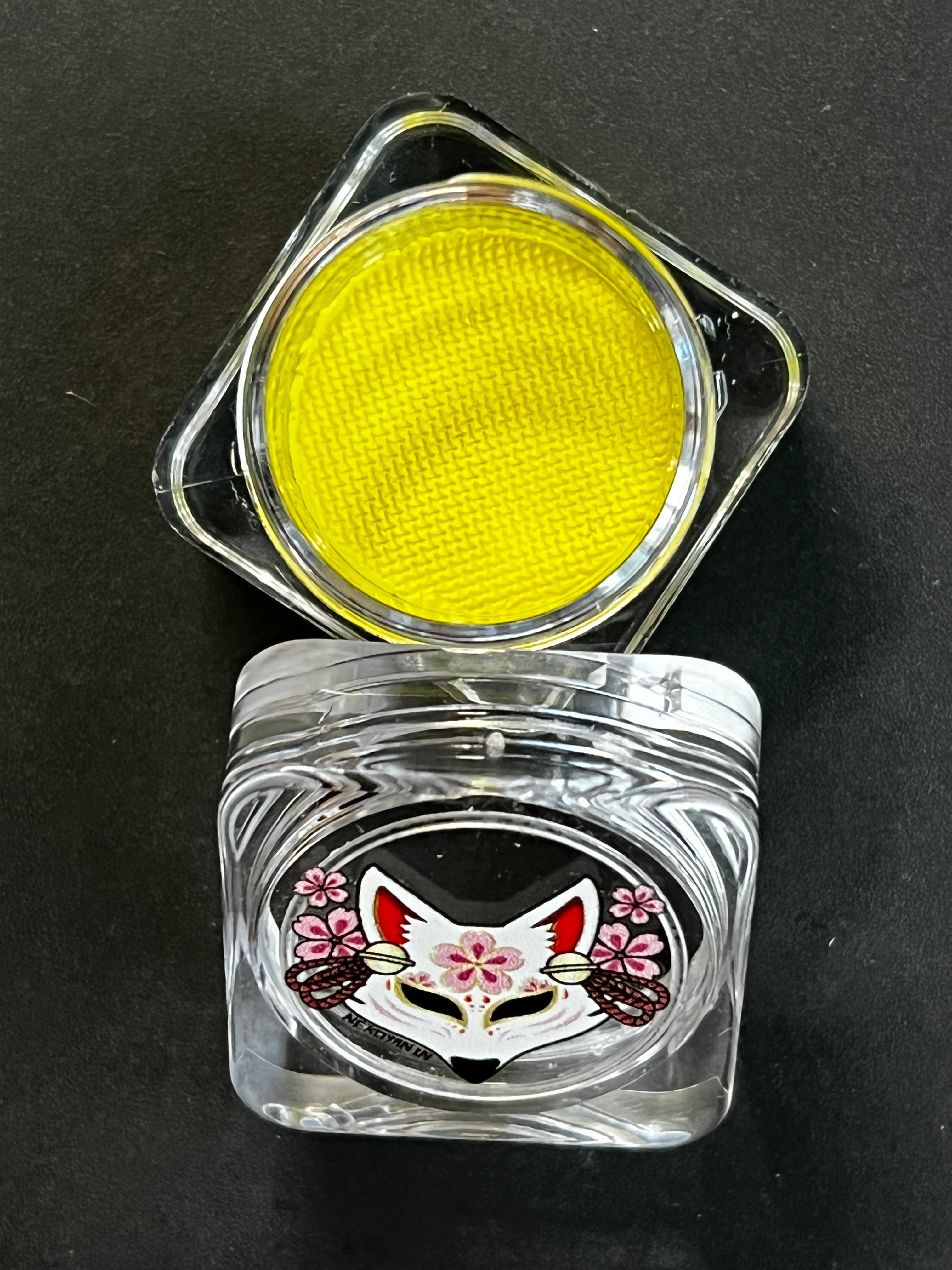 Nekoyanin 15 Dijon yellow water-activated graphic eyeliner, shown with vibrant yellow color and detailed design on white background.