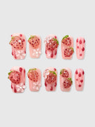 Nekoyanin strawberry shortcake press-on nails with pink and red strawberry designs on a clear base, showcasing a cute, decorative manicure.