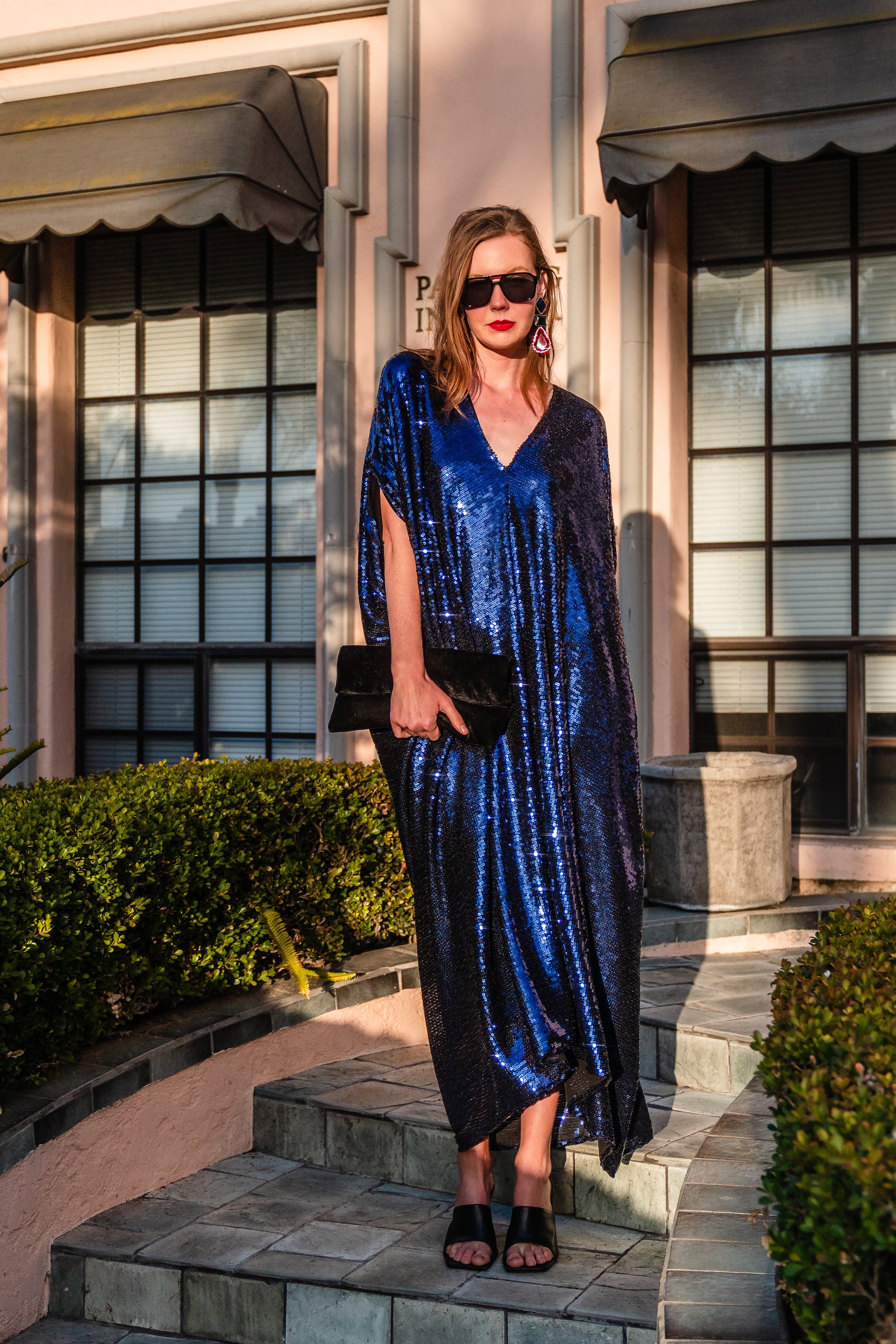 Night sapphire sequin caftan dress by Jennafer Grace featuring shimmering sequins and flowing fabric, displayed on a hanger.