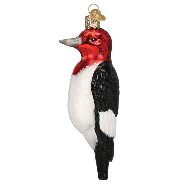 Red-headed Woodpecker ornament from Old World Christmas featuring detailed glass craftsmanship and vibrant red and black coloring.