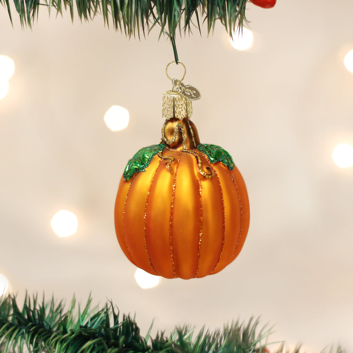 Old World Christmas pumpkin ornament featuring a vibrant orange pumpkin with detailed carving and a festive design.