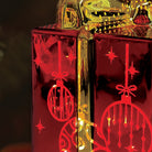 Old World Christmas lit ornamental glass gift box with intricate design and vibrant colors, perfect for holiday decor.