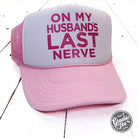 Pink and white foam trucker cap with "On My Husband's Last Nerve" slogan from The Graphic Tee, featuring mesh back and curved brim.