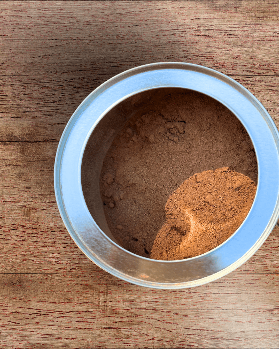 Ora Cacao Triple Fat Cacao Powder in a 12 oz tin, showing the dark, rich cacao powder inside the container.