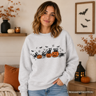 Black sweatshirt featuring spooky skeleton cats and pumpkins for Halloween, with a comfortable fit and festive fall design.