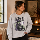 Ash gray Tad Bit Wicked Frog Witch sweatshirt featuring a spooky Halloween cauldron design by OrnamentallyYou.