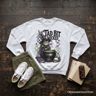 Ash gray Tad Bit Wicked Frog Witch sweatshirt featuring spooky Halloween cauldron design from OrnamentallyYou.