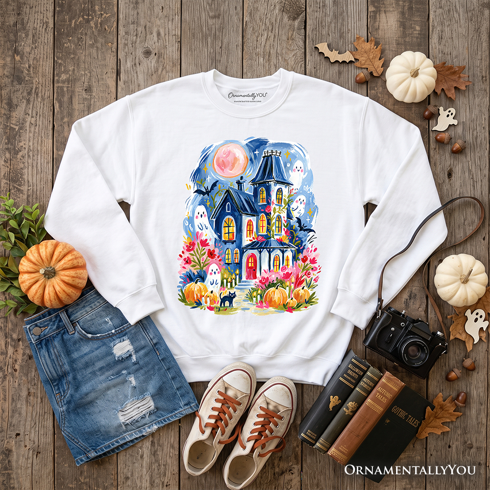 Colorful watercolor haunted house sweatshirt with ghost and pumpkin Halloween design by OrnamentallyYou, featuring spooky autumn imagery.