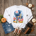 Colorful watercolor haunted house sweatshirt with ghost and pumpkin Halloween design by OrnamentallyYou, featuring spooky autumn imagery.