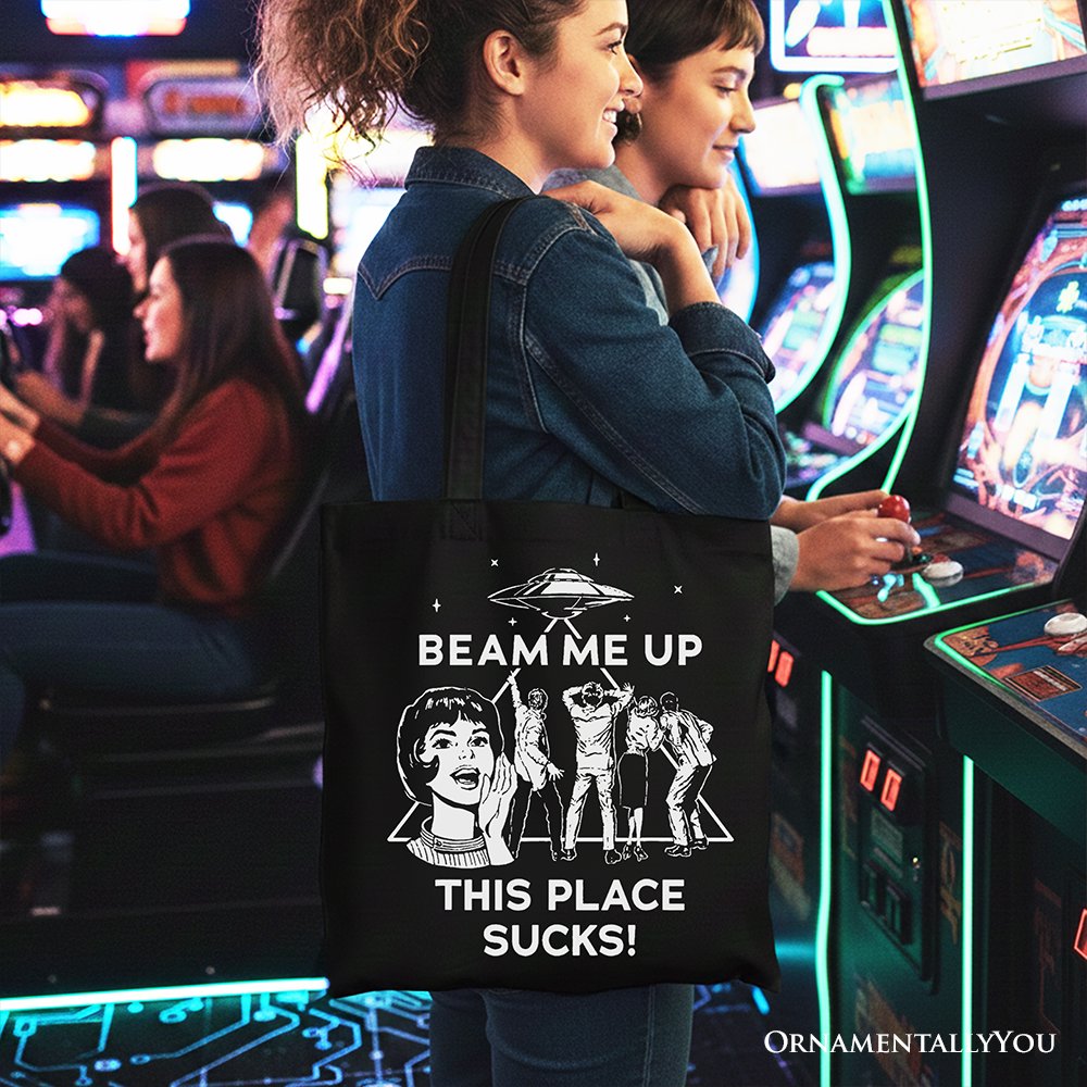 Black canvas tote bag featuring a retro UFO meme with sarcastic "Beam Me Up, This Place Sucks" text, perfect for women shoppers.