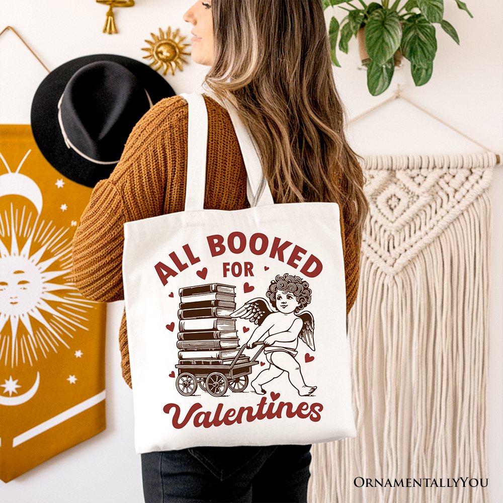 White canvas tote bag featuring "All Booked For Valentines" Cupid design by OrnamentallyYou, perfect for book lovers and vintage gift fans.