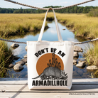 White canvas tote bag featuring a humorous armadillo design, perfect for casual shopping and Western-themed gift-giving.