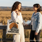 White canvas tote bag featuring humorous "Don’t Be An Armadillhole" armadillo design, perfect for casual shopping or gifting.