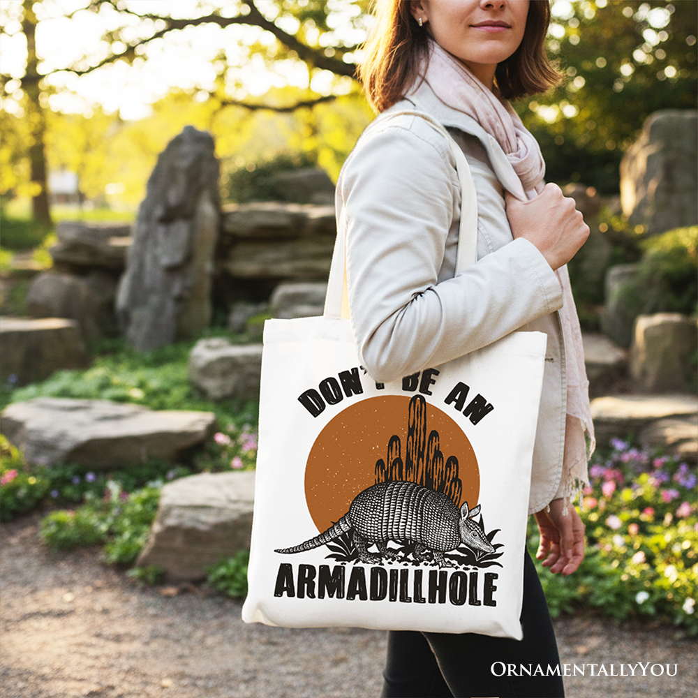 White canvas tote bag featuring a humorous armadillo design from OrnamentallyYou, perfect for shopping or casual outings.