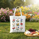 White Christian floral canvas tote bag with "It Is Well With My Soul" Bible verse design by OrnamentallyYou.