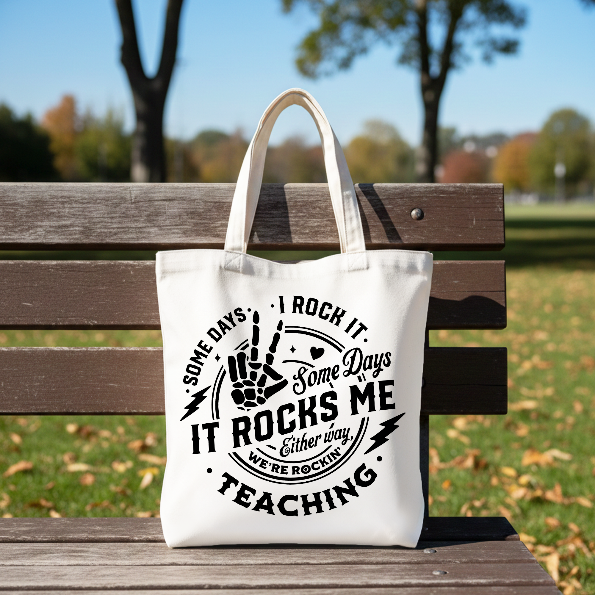 White tote bag with humorous "Some Days I Rock It, Some Days It Rocks Me" text, perfect for teachers and fun gift shoppers.