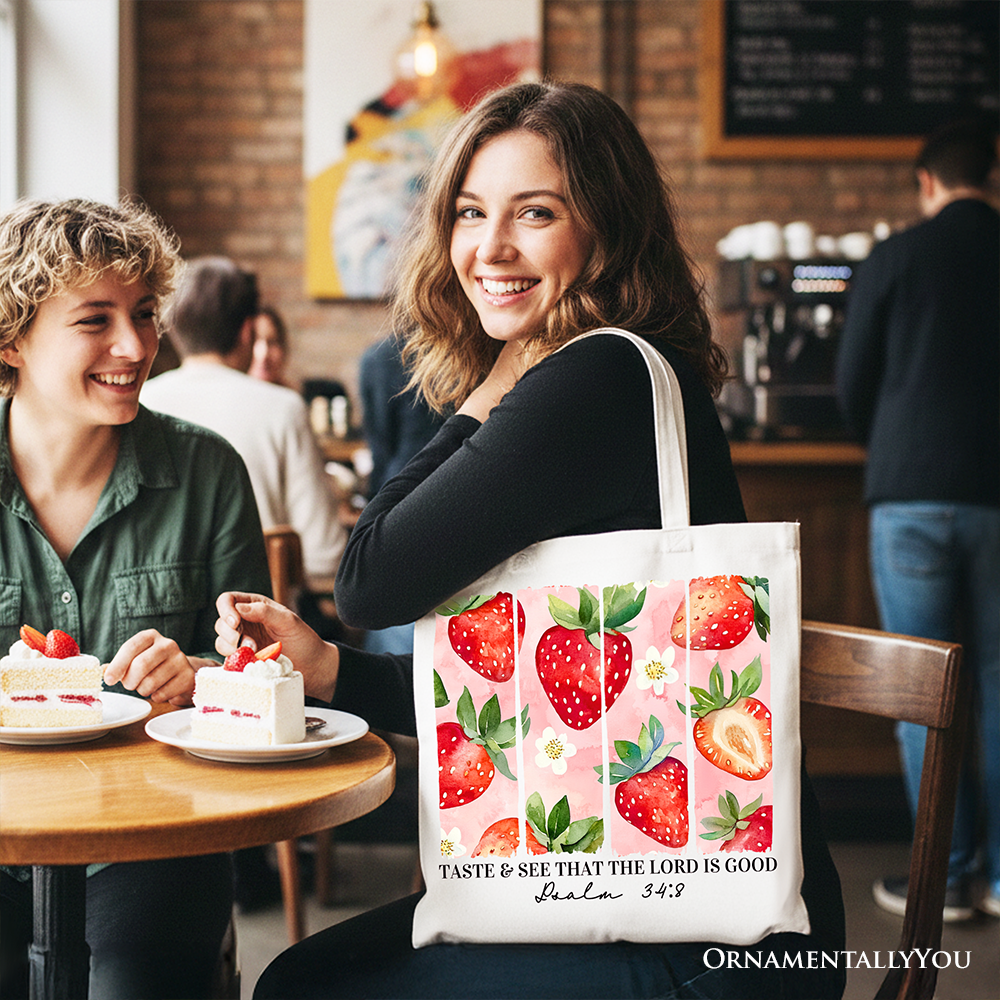 White Christian tote bag with "Taste and See That The Lord is Good" printed on strawberry-themed canvas, ideal for faith gifts.