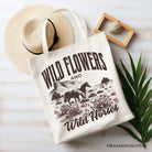 White canvas tote bag with wildflowers and wild horses print, featuring a retro western design, by OrnamentallyYou.