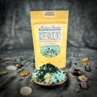 Small jar of Santa Muerte Bath Crystals by Parlour of Wonders, showing colorful crystalline bath salts in clear container.