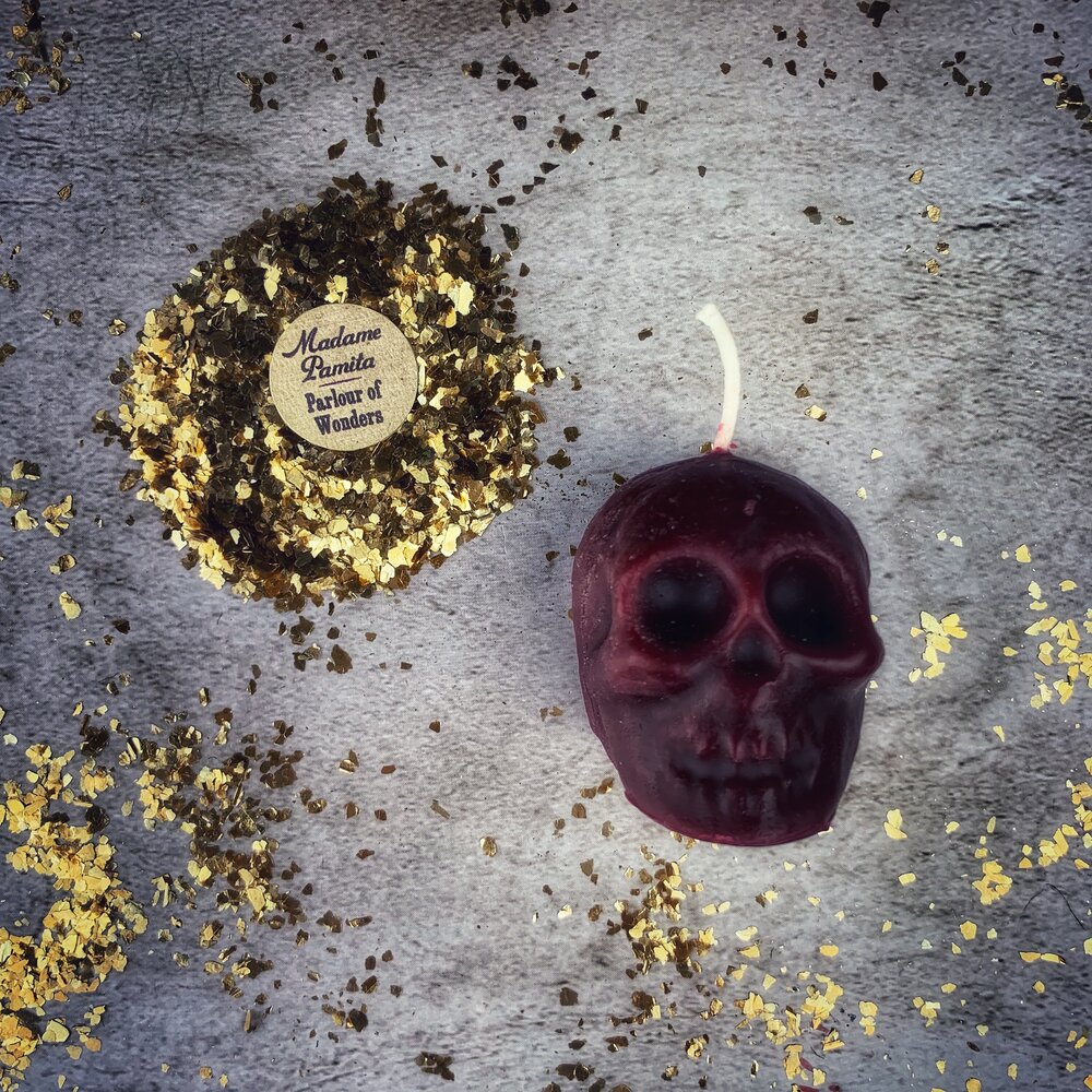 Small orange beeswax skull candle with carved details, used for mind influence and ancestral wisdom magic.