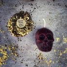 Small orange beeswax skull candle with carved details, used for mind influence and ancestral wisdom magic.