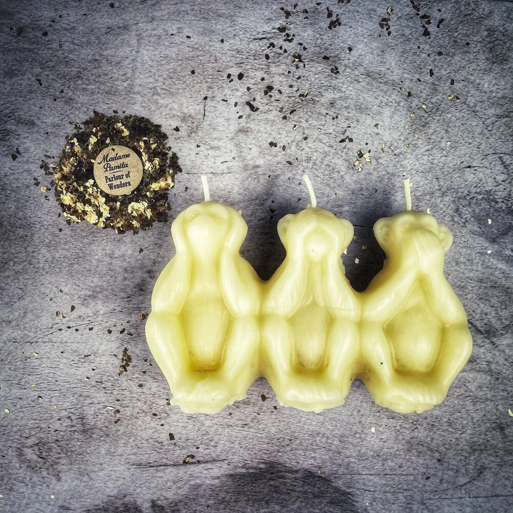 Red beeswax candle featuring three wise monkeys design for protection, silence, and banishing jealousy in spiritual rituals.