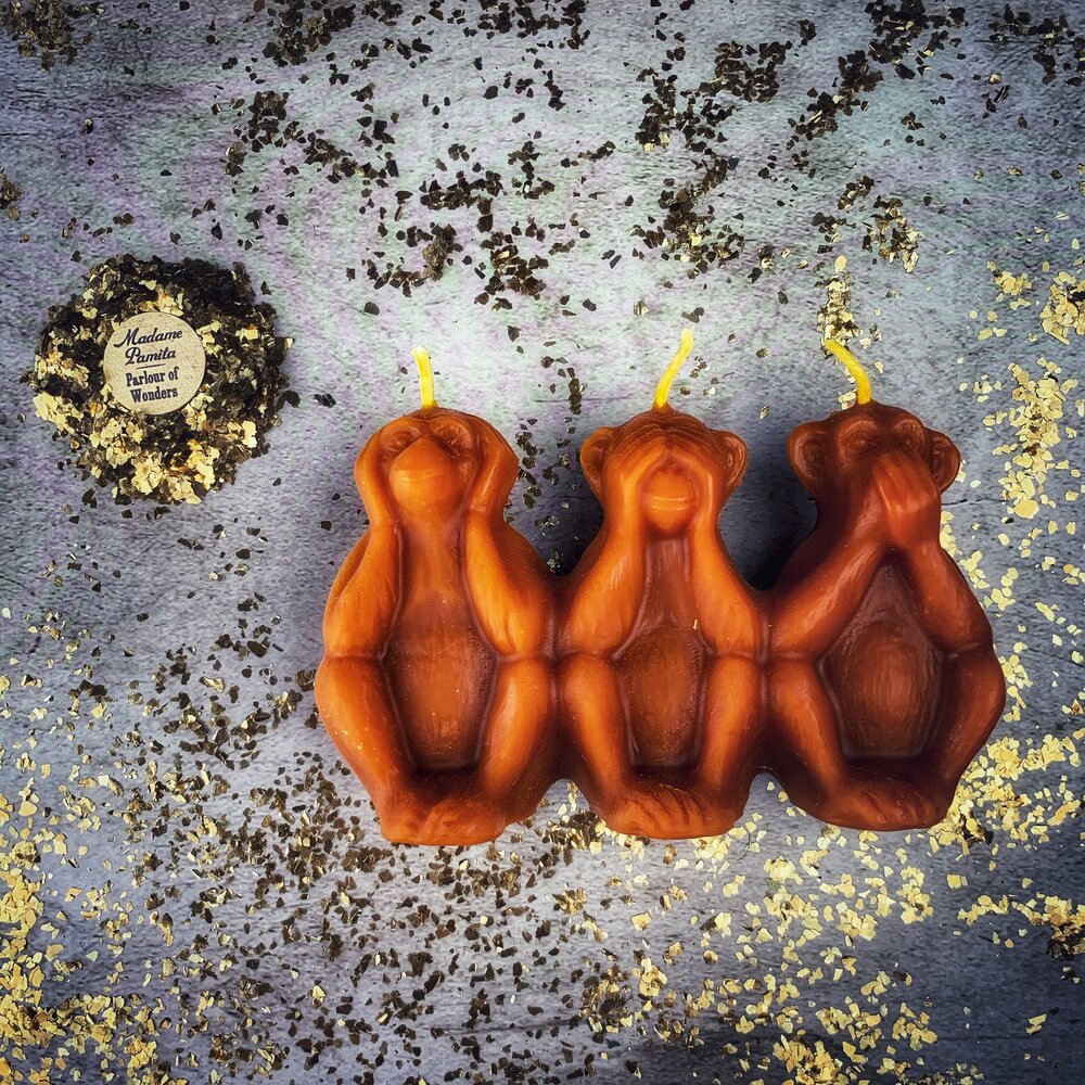 Red beeswax candle featuring three wise monkeys design, used for spell work to stop jealousy, gossip, and silence enemies.