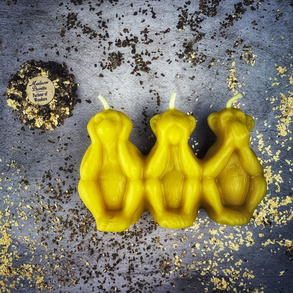Red beeswax candle featuring three wise monkeys design for protection, silence, and stopping gossip, by Parlour of Wonders.