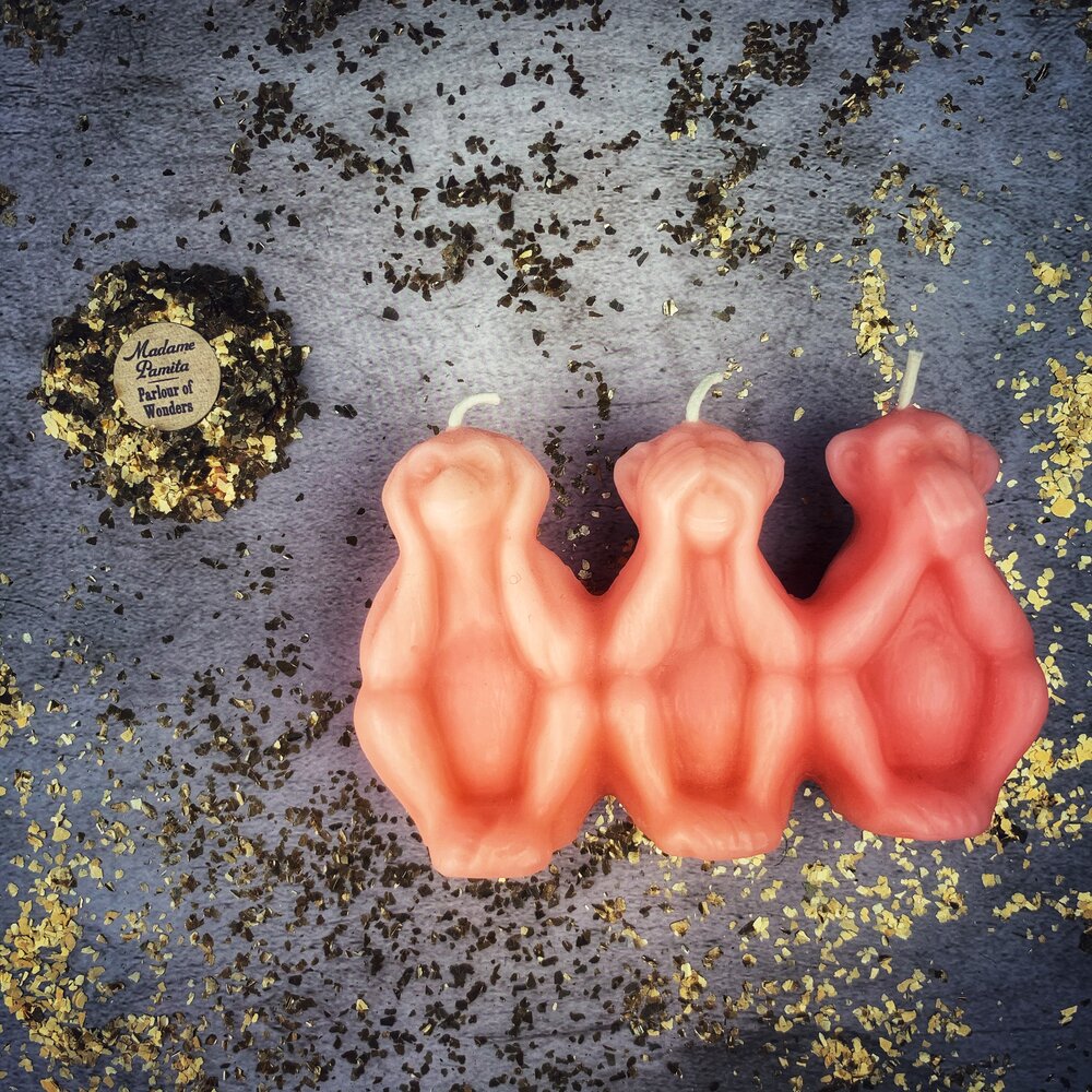 Red beeswax candle featuring three wise monkeys symbol, used for stopping jealousy, gossip, and silencing enemies, by Parlour of Wonders.