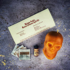 Orange Skull Candle Spell Kit for mental influence and clarity by Parlour of Wonders, featuring a skull-shaped candle and ritual accessories.