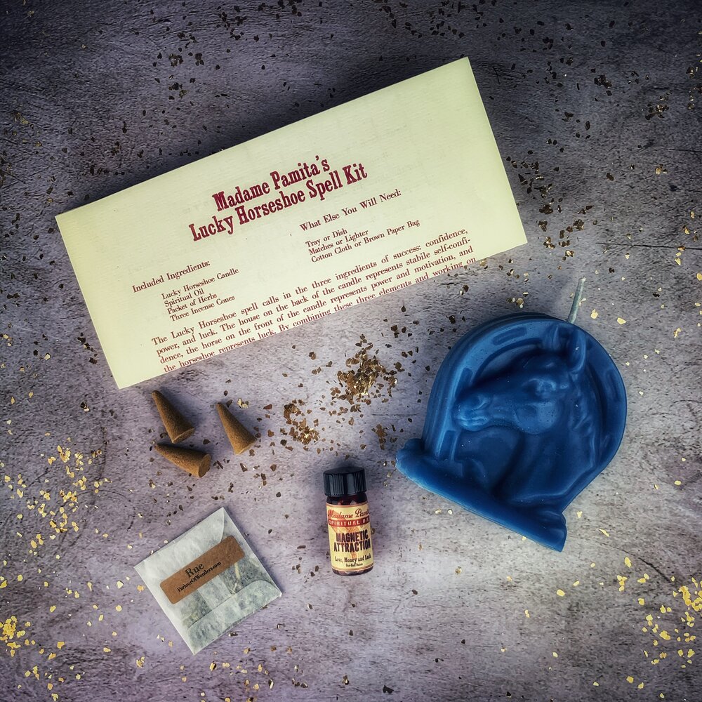 Red candle and horseshoe charm from Parlour of Wonders Lucky Horseshoe Candle Spell Kit for luck and power magic.