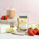 Cup of Plum Deluxe Gratitude Blend Strawberry Earl Grey tea with fresh strawberries and citrus slices in a clear glass mug.