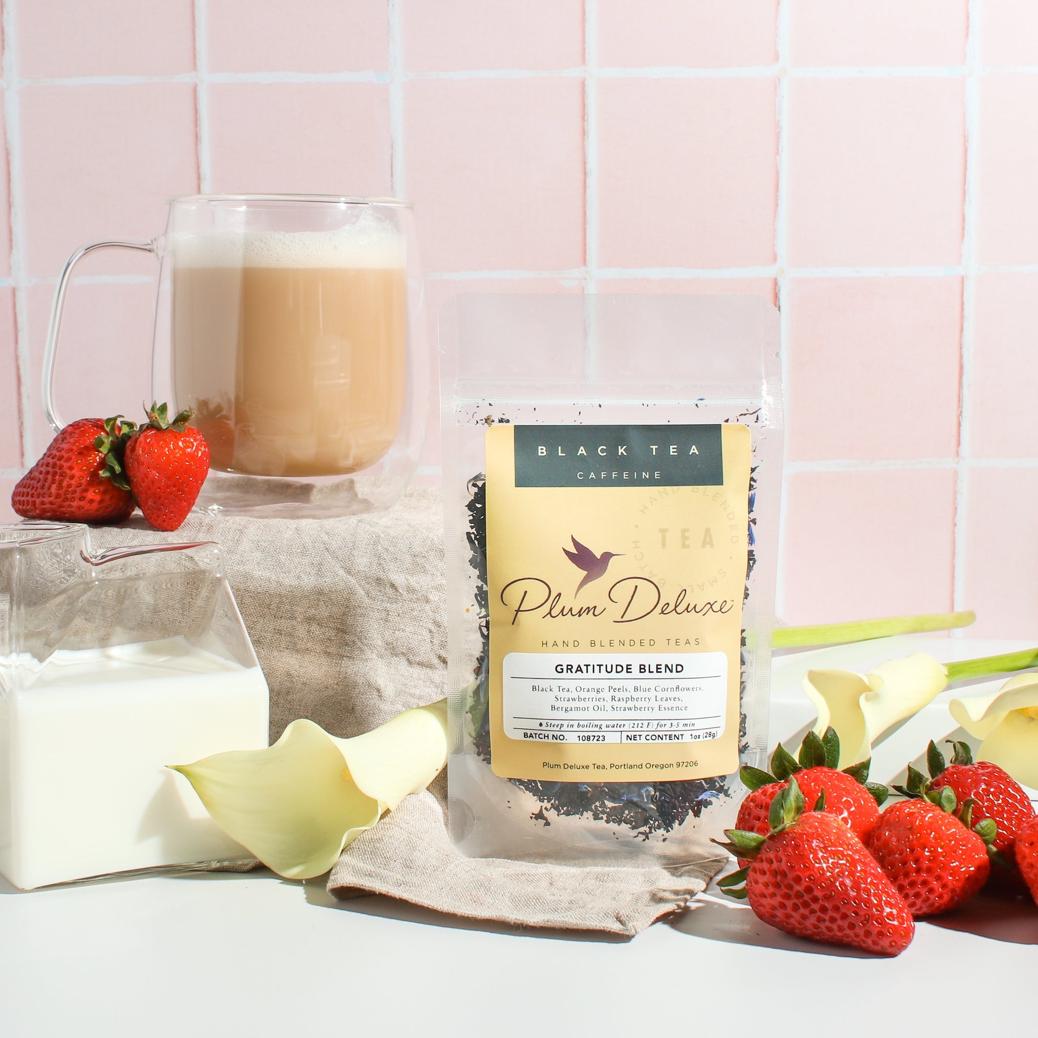 Cup of Plum Deluxe Gratitude Blend Strawberry Earl Grey tea with fresh strawberries and citrus slices in a clear glass mug.