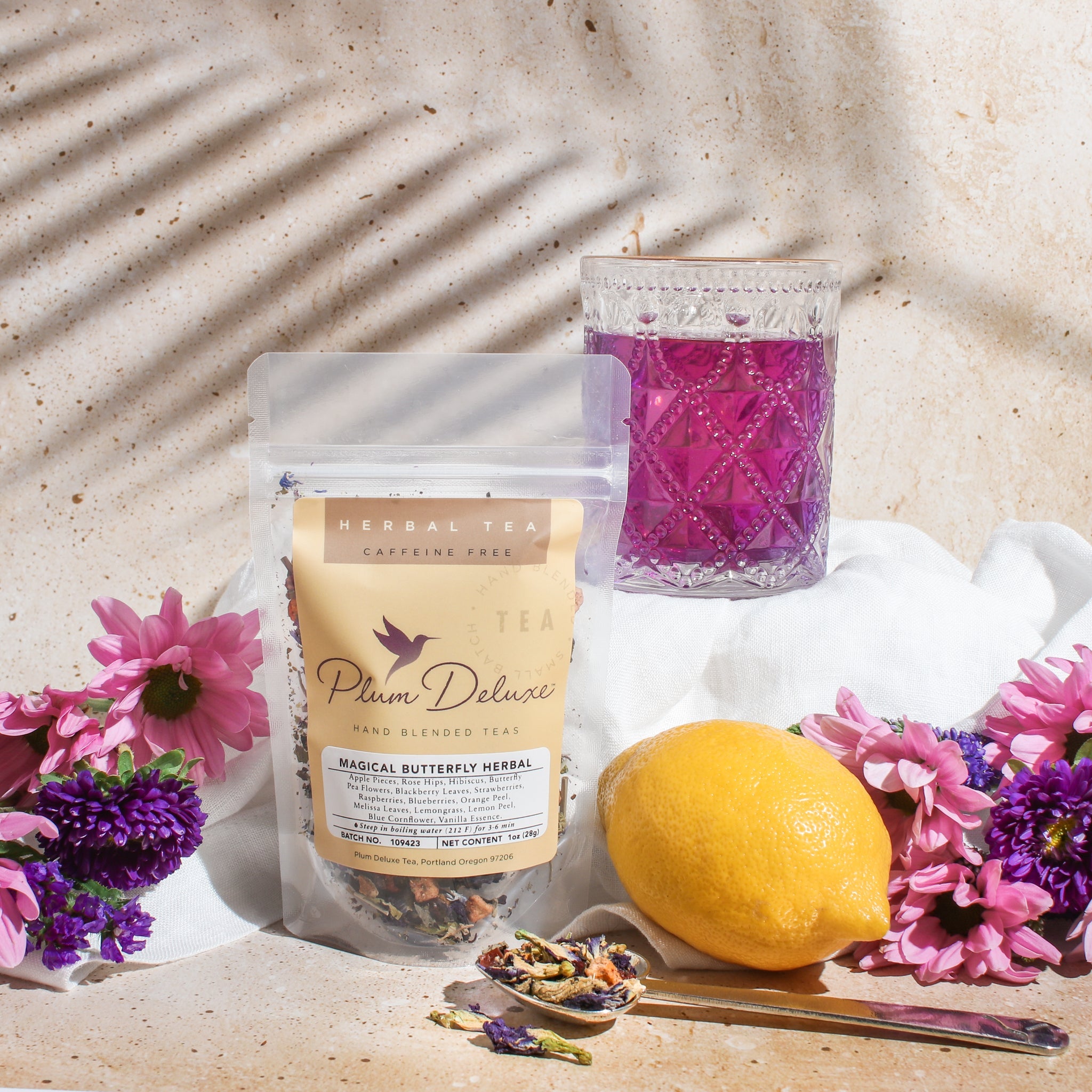 Plum Deluxe Butterfly Herbal Tea with butterfly pea flower and berries in a clear glass cup, showcasing vibrant blue and berry colors.