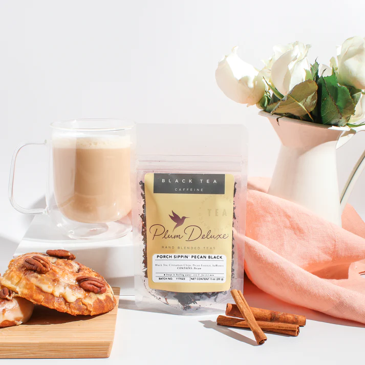 Plum Deluxe Porch Sippin' Pecan Black Tea in a clear glass teacup with brewed tea and pecan pieces, showcasing the tea's rich color.