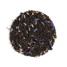 Cup of Plum Deluxe Tea's Delightful Morning Blend Earl Grey Lavender with tea leaves and lavender flowers on a wooden table.