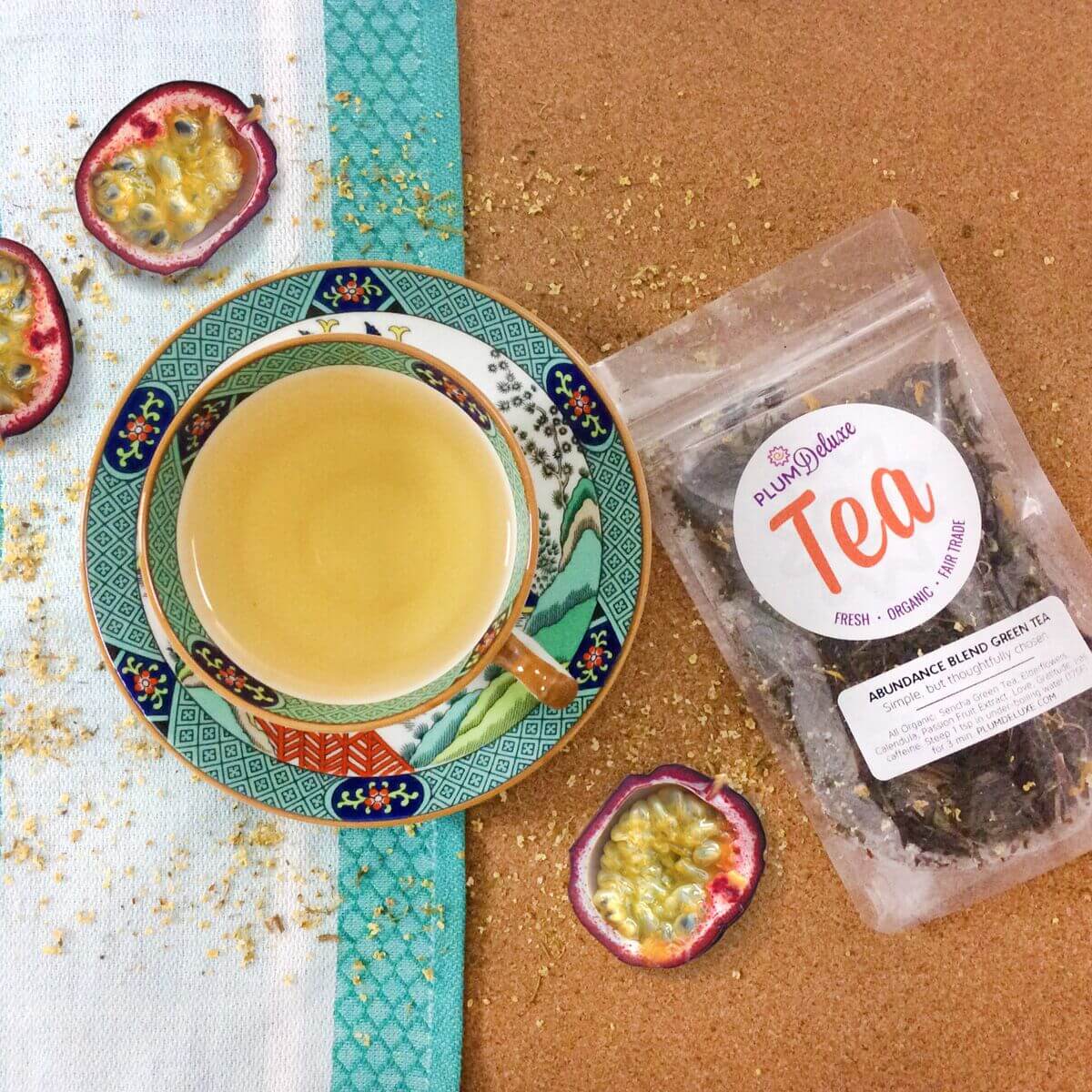 Green tea blend with passionfruit and elderflower from Plum Deluxe, featuring fresh, vibrant ingredients in a colorful package.