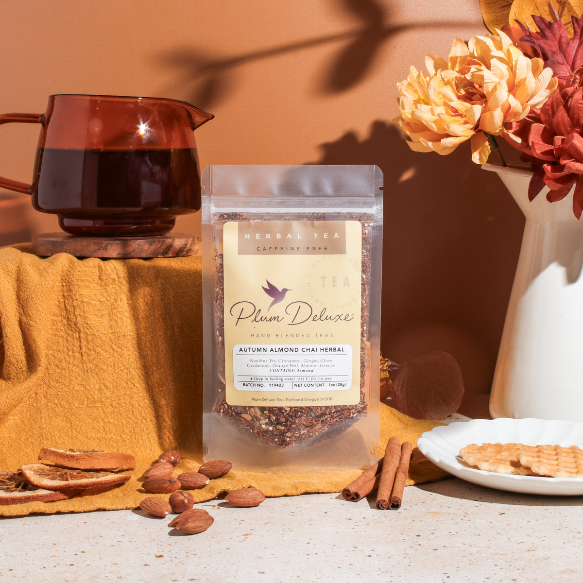 Autumn Almond Chai Herbal tea by Plum Deluxe Tea in a clear glass mug with cinnamon sticks and almonds.