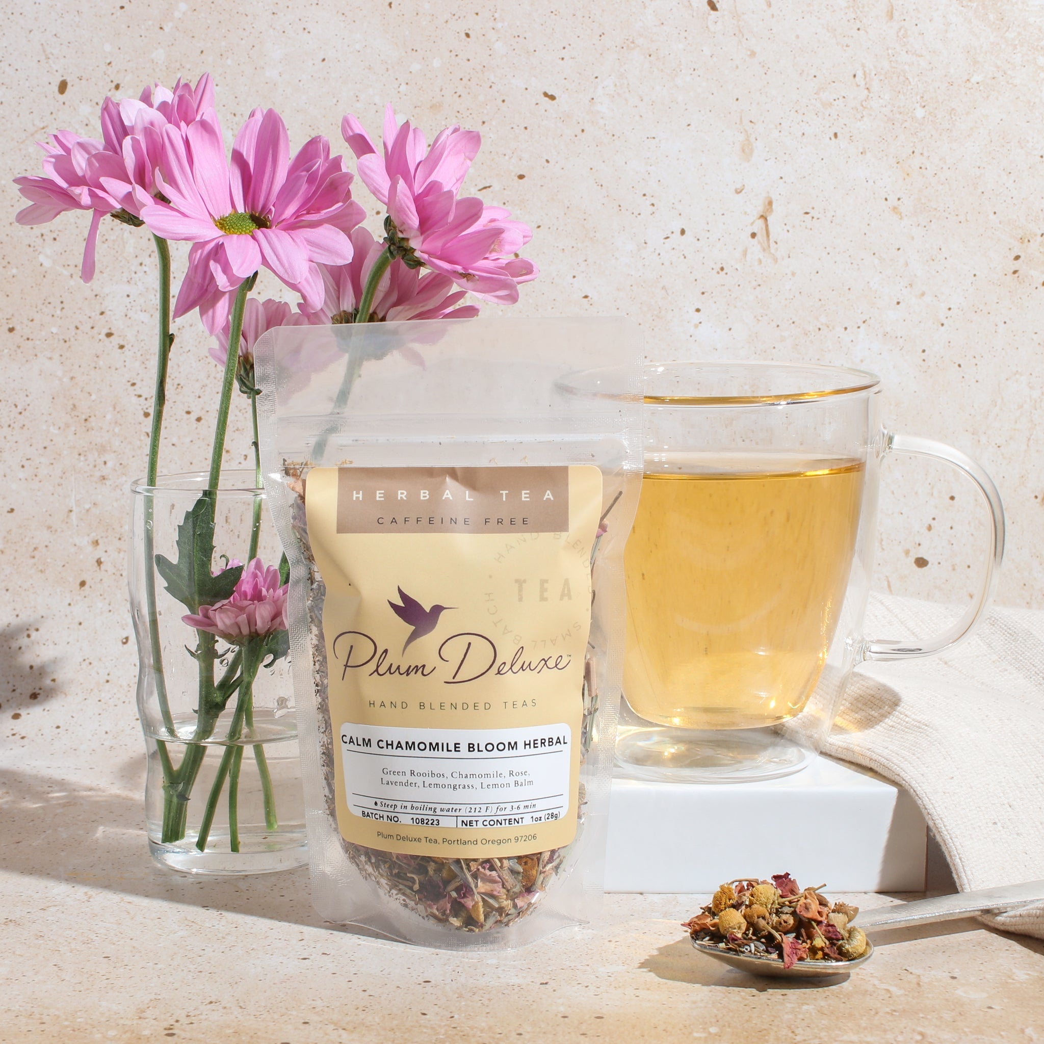 Calm Chamomile Bloom Herbal Tea by Plum Deluxe, with rose and lavender ingredients, in a clear tea infuser.