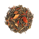 Glass cup of Plum Deluxe Candied Orange Green Tea with orange slices and green tea leaves in a cozy setting.