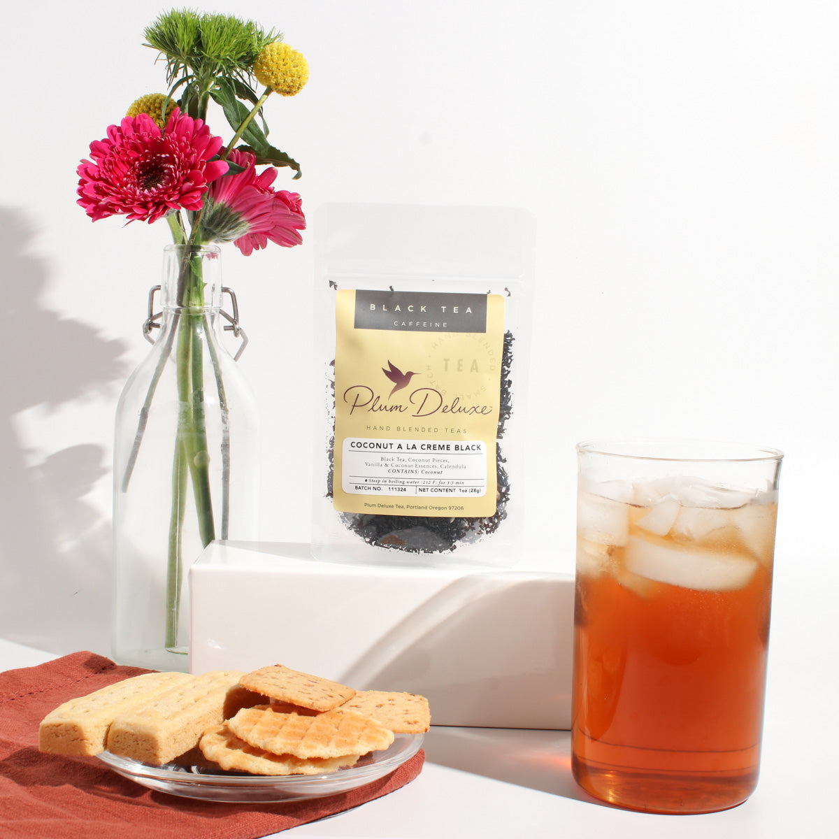 Coconut A La Creme Black Tea by Plum Deluxe, showing a steaming cup of creamy coconut-flavored black tea with tea leaves.